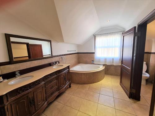 a bathroom with two sinks and a tub and a toilet at One Rawdons Estate in Nottingham Road