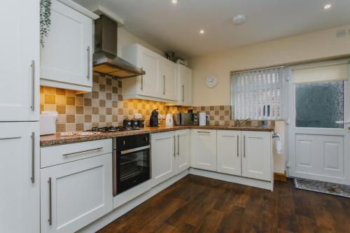 cocina blanca con suelo de madera y armarios blancos en Home from Home 1 king size bed Apartment Near Hospital & Tennis en Nottingham