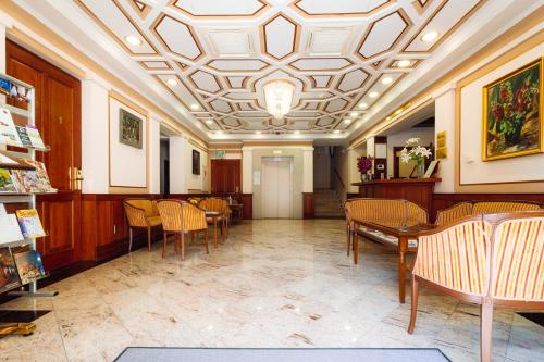 a waiting room with tables and chairs and a ceiling at Hotel Ködmön in Eger