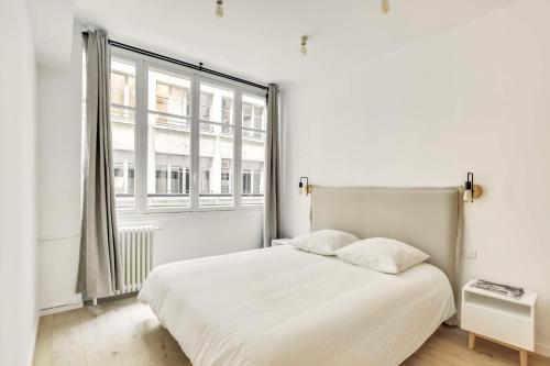 une chambre avec un lit blanc et une grande fenêtre dans l'établissement Central & Stylish renovated Parisian apt / 6-8 guests, à Paris