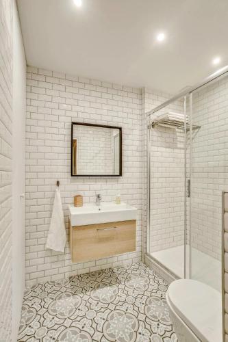 une salle de bain blanche avec un lavabo et une douche dans l'établissement Central & Stylish renovated Parisian apt / 6-8 guests, à Paris