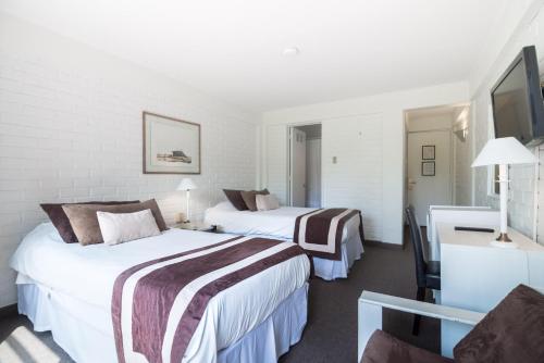 a hotel room with two beds and a television at Hotel Acacias de Vitacura in Santiago
