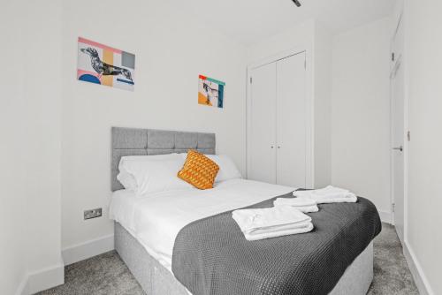 a bedroom with a bed with white sheets and an orange pillow at Roof terrace 2BED Property CAMDEN free WiFi in London