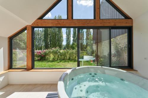 a bath tub in a room with a large window at Maison du Passeur du XVIII siècle Authenticité et Confort avec Jardin et SPA pour un séjour de qualité in Pressagny l'Orgueilleux