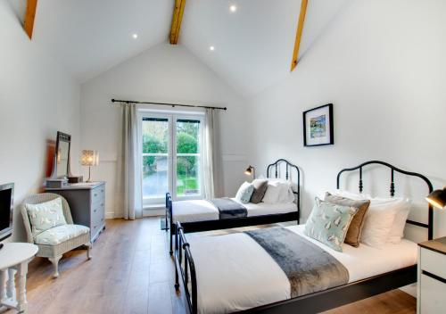a bedroom with two beds and a table and a chair at Roman Bridge Close in Oystermouth