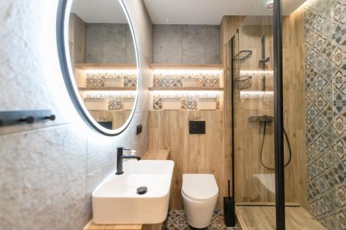 ein Badezimmer mit einem Waschbecken, einem WC und einem Spiegel in der Unterkunft Wisła - Centrum, Apartament z Wiślaczkiem - Dream Apart in Wisła