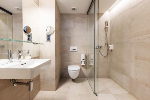 a bathroom with a toilet and a sink and a shower at OREA Hotel Arigone Olomouc in Olomouc
