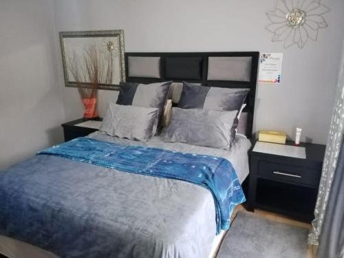 a bedroom with a bed with blue sheets and pillows at Mosaic Guesthouse Welkom in Welkom
