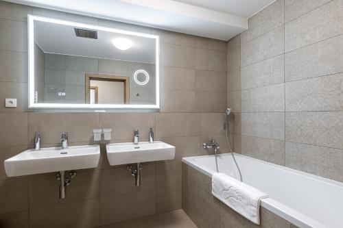 a bathroom with two sinks and a tub and a mirror at Hubertus Karlova Studánka in Karlova Studánka