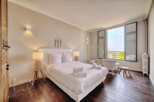 - une chambre avec un grand lit blanc et une grande fenêtre dans l'établissement IMMOGROOM - Large Apartment - Parking - Air conditioning - Sea view - Wifi, à Cannes