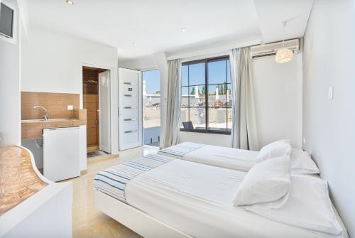 a white bedroom with a large bed and a window at Mando Living -Faliraki in Faliraki