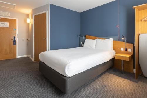 een slaapkamer met een groot bed met een blauwe muur bij Holiday Inn Express Aberdeen City Centre, an IHG Hotel in Aberdeen