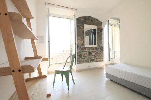 une chambre avec un lit, une chaise et une fenêtre dans l'établissement bel appartement lumineux joyeux spacieux, vue mer, à Menton