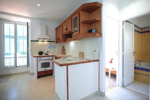 une cuisine avec des armoires en bois et un comptoir dans l'établissement bel appartement lumineux joyeux spacieux, vue mer, à Menton