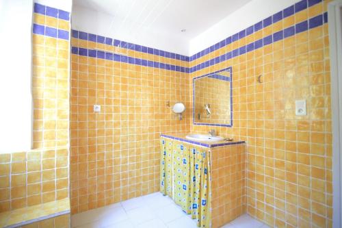 - une salle de bains carrelée de jaune avec lavabo et miroir dans l'établissement bel appartement lumineux joyeux spacieux, vue mer, à Menton