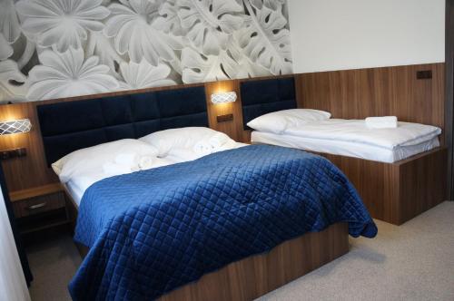 a bedroom with two beds with a blue blanket at Hotel Biele Studničky Dargov in Dargov
