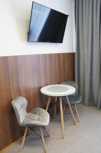 a table with two chairs and a tv on a wall at Hotel Biele Studničky Dargov in Dargov