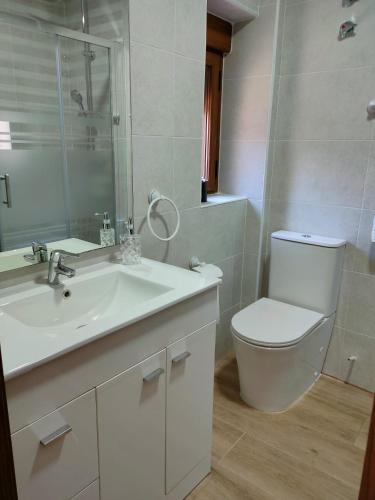 a white bathroom with a toilet and a sink at Casa Valentín in Casillas