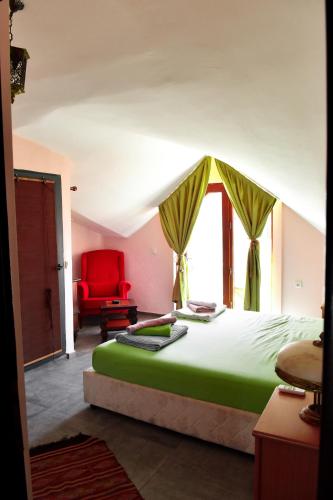 a bedroom with a green bed and a red chair at Smyrna Pansiyon in Kaş