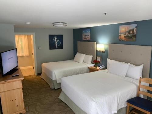 a hotel room with two beds and a television at The Lodge at Turbat's Creek in Kennebunkport
