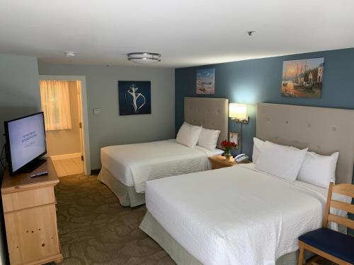 a hotel room with two beds and a television at The Lodge at Turbat's Creek in Kennebunkport