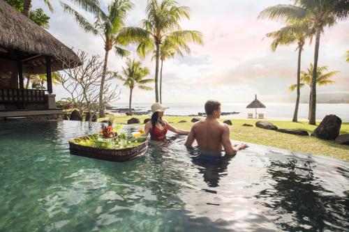 a man and woman sitting in a swimming pool at a resort at Shanti Maurice Resort & Spa in Bel Ombre