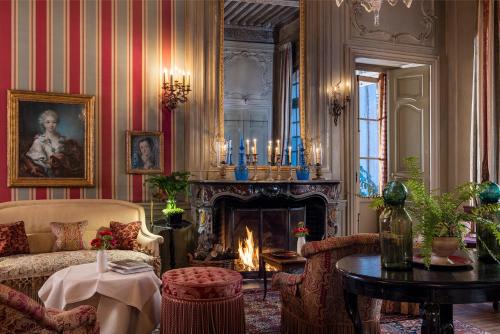 a living room with a fireplace and a couch and a table at La Mirande in Avignon