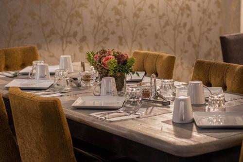 a long table with plates and glasses and a vase of flowers at Hôtel Littéraire Gustave Flaubert, BW Signature Collection in Rouen