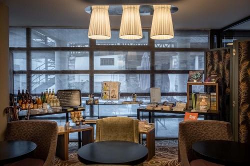 a restaurant with tables and chairs and a large window at Hôtel Littéraire Gustave Flaubert, BW Signature Collection in Rouen