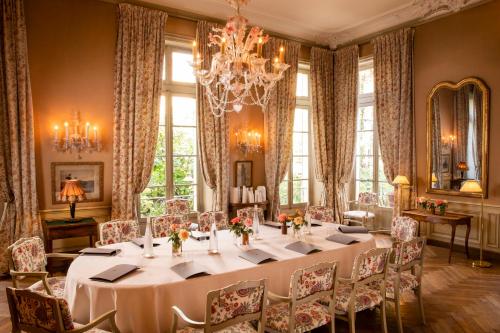 a dining room with a table and chairs and a chandelier at La Mirande in Avignon