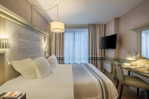 a hotel room with a large bed and a desk at Hôtel Littéraire Gustave Flaubert, BW Signature Collection in Rouen