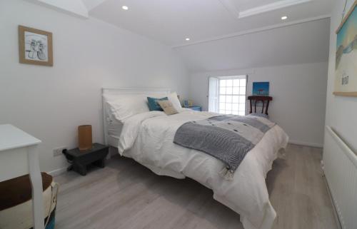 a white bedroom with a large bed and a window at Sea la Vie in Newcastle