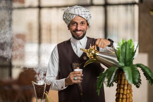 a man is holding a drink in a drink mixer at Elaf Al Taqwa Hotel in Al Madinah