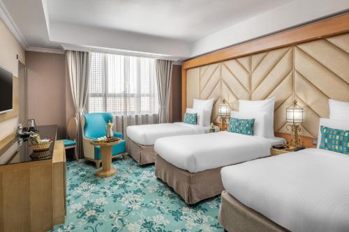 a hotel room with two beds and a television at Elaf Al Taqwa Hotel in Al Madinah