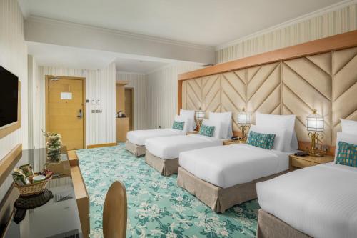 a hotel room with three beds and a television at Elaf Al Taqwa Hotel in Al Madinah