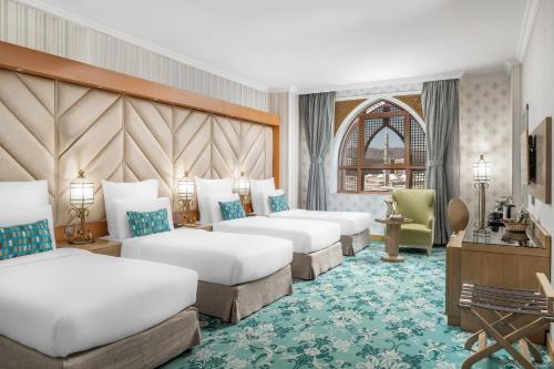 a hotel room with four beds and a desk at Elaf Al Taqwa Hotel in Al Madinah