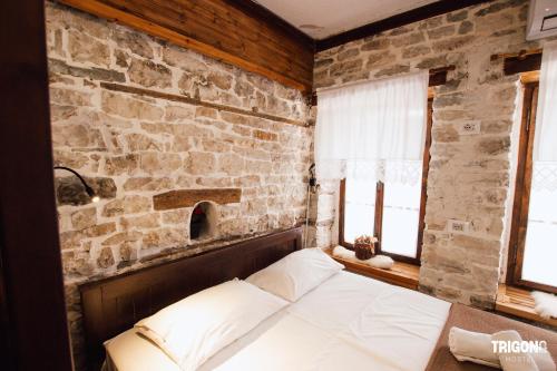 a bed in a room with a stone wall at Trigona Guest House & Hostel in Gjirokastër