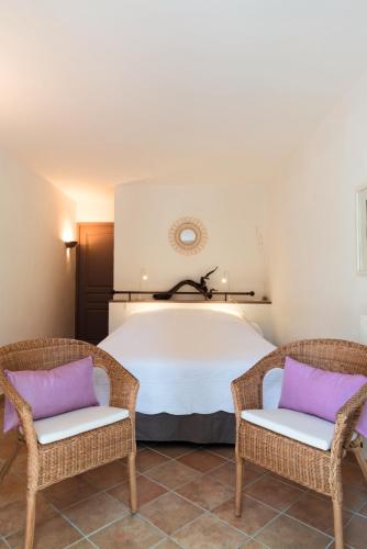 a bedroom with a large bed with two chairs at Bastide de Fave in Brue-Auriac