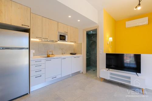 a kitchen with white cabinets and a flat screen tv at De Mar Village Apartments, Agios Nikolaos in Agios Nikolaos