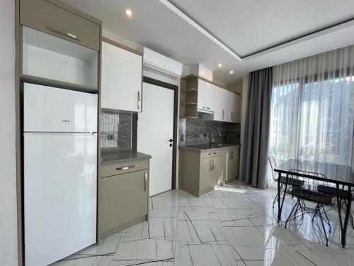 Il comprend une cuisine équipée d'un réfrigérateur blanc et d'une table. dans l'établissement LOTUS Apart, à Kusadası