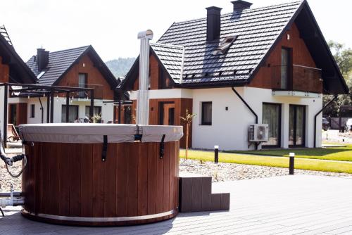 a large wooden tub in front of a house at Dolina Barw - całoroczne domki na wynajem in Rabka