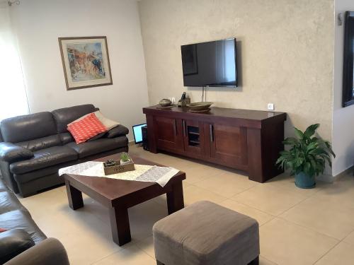 a living room with a couch and a flat screen tv at וילה נוף הרים שלומי in Shlomi