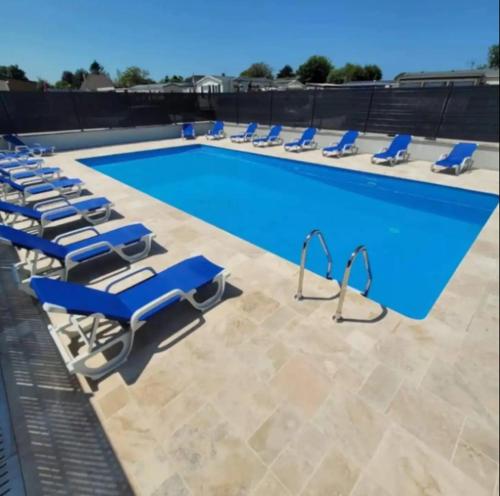 a swimming pool with blue lounge chairs next to it at Bienvenue chez Anaïs ! in Biville-sur-Mer