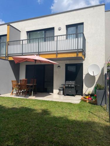 a patio with an umbrella and a table and a grill at Sunny apartment on the lakes in Senec