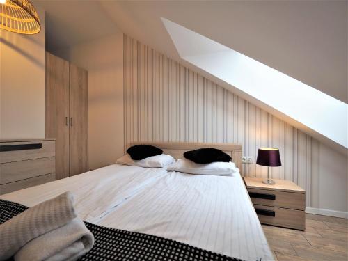a bedroom with a large white bed with a sloped ceiling at VIP Apartamenty Stara Polana 2 in Zakopane