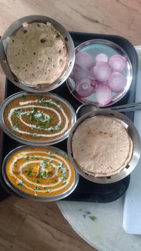 a bunch of different types of food in pans on a table at Hari Om Paradise in Kūfrī