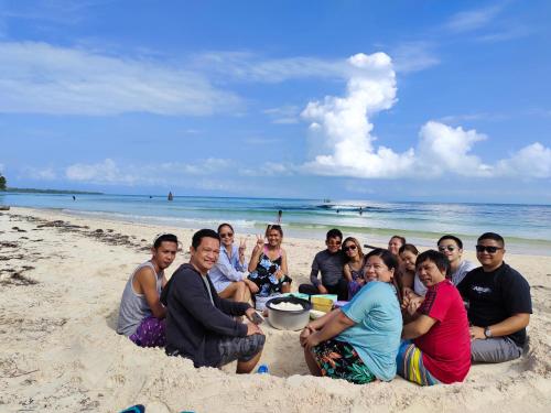 a group of people sitting in the sand on the beach at Payag n' Kapitan, Experience pinubre living in Siquijor