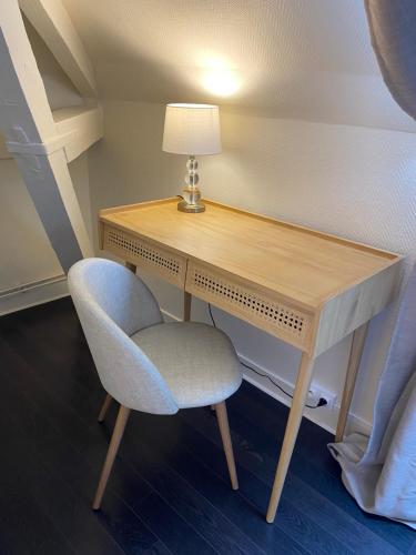 a desk in a room with a chair and a lamp at Hotel l'Avenue in Chantilly