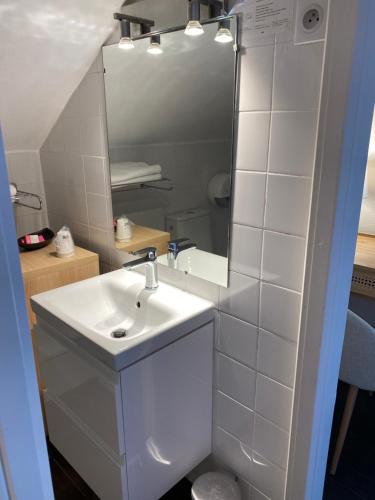 a white bathroom with a sink and a mirror at Hotel l'Avenue in Chantilly