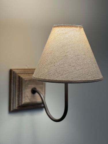 a lamp with a shade attached to a wall at Hotel l'Avenue in Chantilly